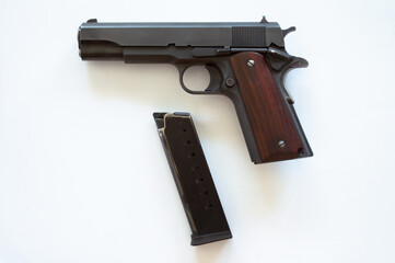 Black metal pistol. Wood handle. Left side view. Empty white background. Magazine taken out. Unloaded. Close view