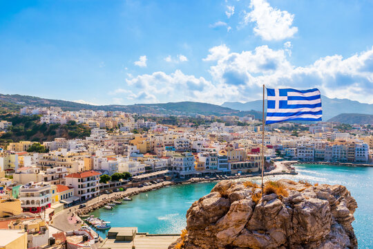 Panoramic view of Pigadia bay, town and harbor with Greek flag, Karpathos Island, Greece