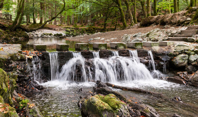 Fast flowing river and rapids in a rocky riverbed in a natural park. Early autumn landscape.
