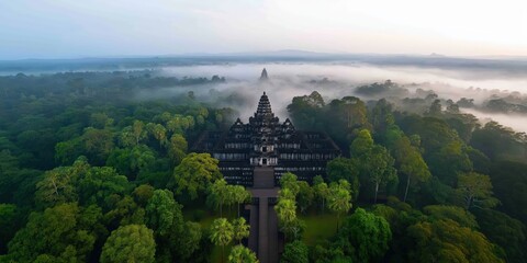A wide-angle shot capturing the entire temple complex surrounded by lush trees, with soft morning mist lingering
