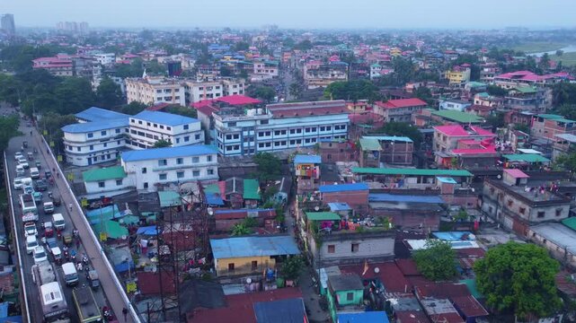 Siliguri city densely populated residential neighbourhood with historical hillcart road traffic movement under hazy sky, West Bengal, Establishing drone shot
