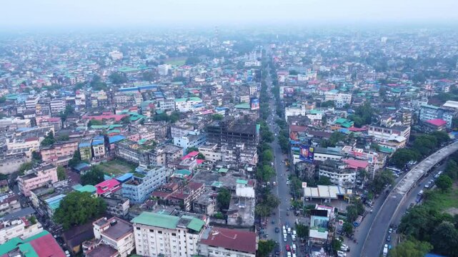 Siliguri densely populated cityscape under hazy sky due to air pollution on the banks of Mahananda and Teesta River in the foothills of Himalayas, Hill Cart road traffic movement, Drone view