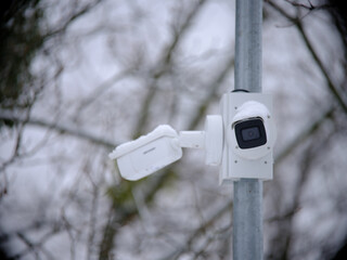 A close-up of a surveillance camera captures stark detail, ensuring robust monitoring in a snowy landscape, highlighting technology's prowess in security and surveillance.