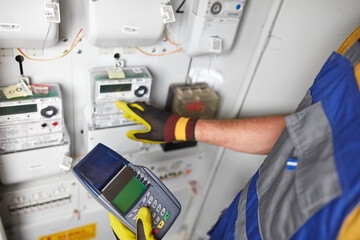 Technician reading consumption and charging on a wireless electricity power meter station in a...