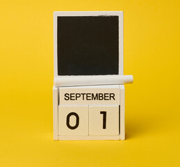 Wooden calendar and white piece of chalk on yellow background