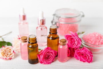 Rose essential oil on a textured background.Roses and a bottle of rose perfumed water.Aromatherapy treatment. Beauty concept. Spa procedure.Natural organic oil.Anti-stress,detox relax.Place for text