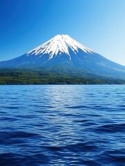 Fototapeta premium A stunning view of a snow-capped mountain towering over a serene blue lake, under a clear sky.