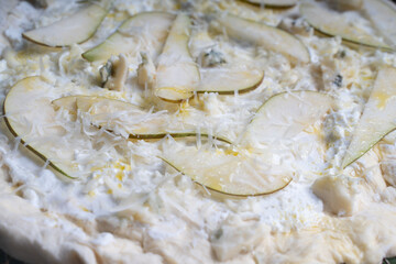 Pizza textured background with pear and gorgonzola and parmesan cheese. Raw pizza in a curly plan.