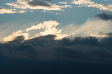 Clouds gather over the horizon as sunlight breaks through during a serene evening in the countryside