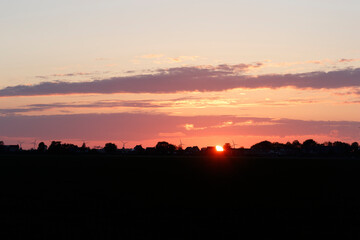 Beautiful sunset illuminating the sky above the horizon in a rural landscape during twilight