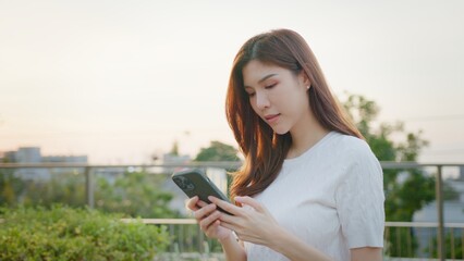 Happy woman texting on a phone. Happy young asian woman talking on the mobile phone and smiling. The concept of using the phone is essential in everyday life, browsing social networks