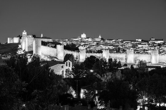 Fototapeta Twilight skyline of Ávila old town surrounded by the medieval defense wall in Ávila, Castilla y Leon, Spain in black and white