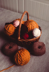 Colorful balls of soft yarn are kept in a wooden basket at home. They are the materials used for crocheting.