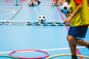 Indoor soccer training class for children. Physical education class for school kids. Children improving agility. Soccer skills training. Futsal players in practice game at sports hall