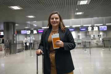 Portrait of Caucasian traveler woman hold ticket ready enjoy voyage tour passenger walk in airport terminal to boarding gate. Attractive beautiful female tourist excited to go travel abroad by