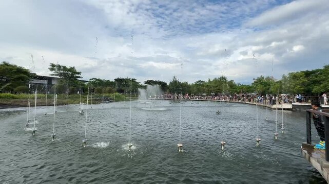 a scenic view of illuminated dancing water fountains  at Kiara Artha Park on a bright sunny day. modern urban park in Bandung with a special show on the lake