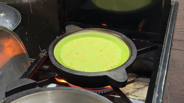 the process of making a martabak by street vendors. famous Indonesian street food. pandan flavour martabak, terang bulan. close up look of the cooking process of a martabak with toppings. sweet snack