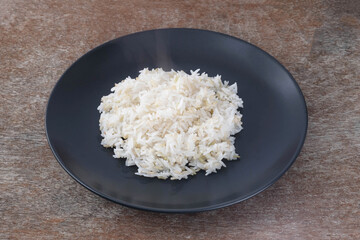 Jasmine rice in a black ceramic dish on a wooden table.
