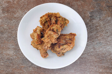 Fried chicken in a white ceramic plate on a wooden table.