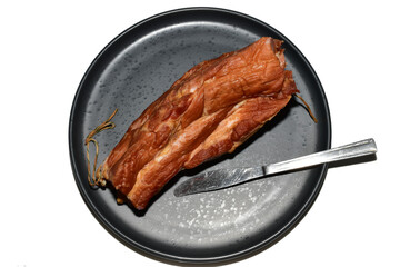 Smoked pork meat lies on a ceramic plate, top view.