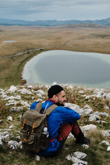 A young backpacker man in the mountains, sitting at the top and enjoying the views of nature and the purest mountain air. Vrazje jezero Devil's Lake - Montenegro country, Durmitor national park.