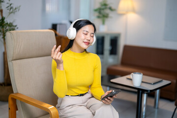 Obraz premium A woman is sitting in a chair with her hands on her face and headphones on