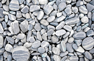 Abstract grey dry round stones background. At the beach. Sea pebbles and gravel style. Top view. Close up.