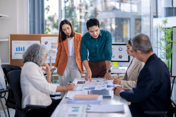 A group of people are gathered around a table with charts and graphs