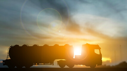 Silhouette photo of long truck with a driver delivery shipping service , transportation and cargo service concept, computer flare light with sunset blur background, copy space for text and design