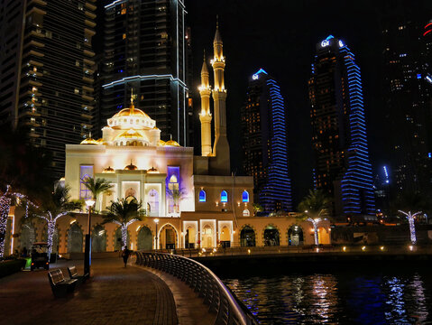 Dubai, UAE - 03 February 2024: The mosque Al Rahim masjid against the backdrop of skyscrapers shines in the dark at night.