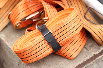 Lashing straps. Trailer strap made of orange nylon and metal tie. Close-up of a load holding strap....