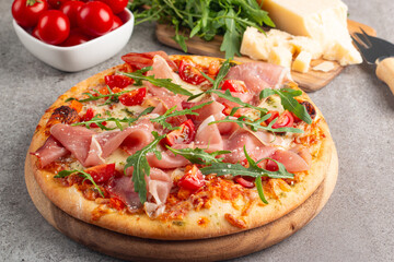 Pizza with prosciutto, ham, arugula, spinach, tomatoes, pesto, cheese and parmesan. Italian cuisine