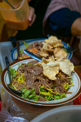 Rujak Juhi: A Betawi salad featuring dried cuttlefish (juhi), yellow noodles, potatoes, cucumber, lettuce, and a peanut sauce dressing, topped with emping crackers.