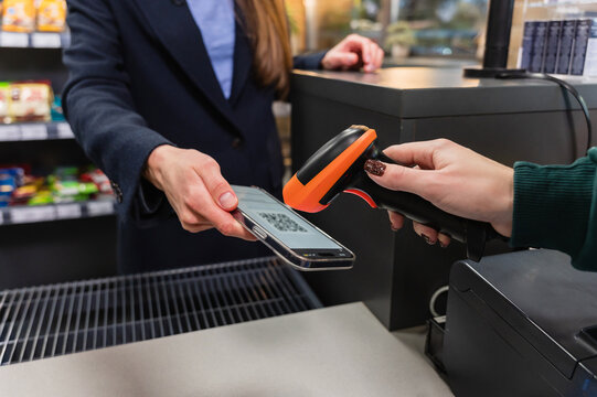 A cashier scans a qr code from a smart phone using a barcode scanner.