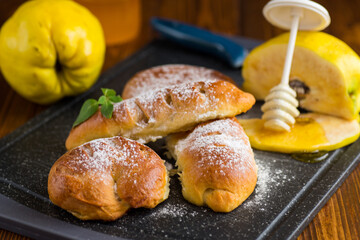 Pastries. Sweet buns with quince and honey filling, on a wooden table