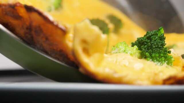 Place hot omelette with vegetables and broccoli in a plate from the frying pan. Vegetarian dinner. Healthy eating concept. Slow motion