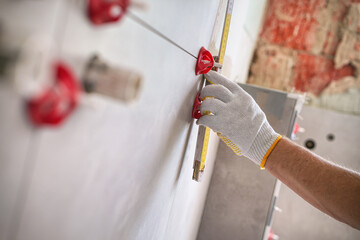 Laying tiles concept. Tiler, spatula and glue when laying tiles with close up hands. Pull tabs and...