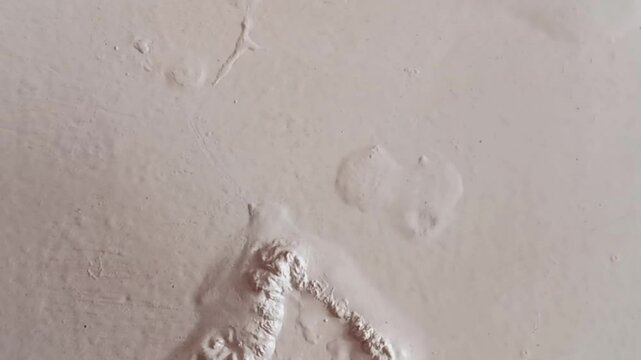 Abstract texture of paint blisters or bubbles on a white wall.