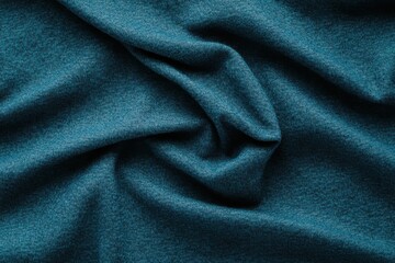Fototapeta premium A close-up view of soft, textured teal fabric, featuring intricate folds and a rich color that suggests warmth and comfort.