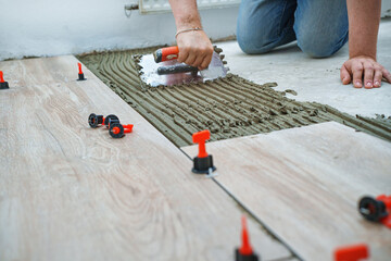Laying tiles concept. Tiler, spatula and glue when laying tiles with close up hands. Pull tabs and...