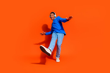 Happy young man jumping joyfully against a vibrant orange background