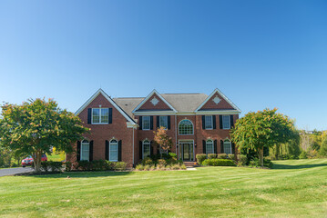Obraz premium Large brick house with a green lawn. Landscape on a summer sunny day.