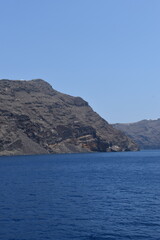 The volcanic crater and rocks of Santorini Island rising from the blue Mediterranean Sea