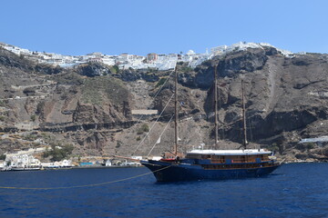 A luxury yacht and sail boat cruising in the crater of Santorini Island in the Mediterranean Sea, Greece