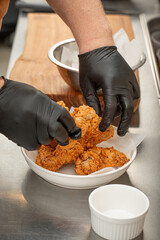 Chef puts the fried chicken wings on a plate to serve