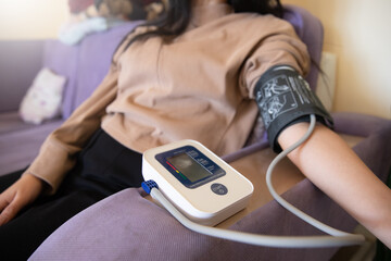  A woman is testing her blood pressure while lying in bed.