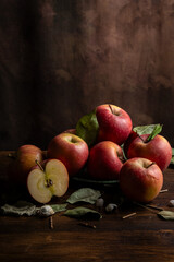 Top view of red apples and dried leaves on table, dark background, vertical, with copy space
