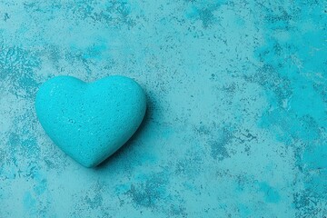 Obraz premium A turquoise heart-shaped stone rests on a textured blue background, evoking feelings of love and tranquility.