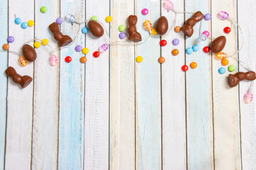 Easter background on wooden planks in pastel colours with Easter lights, eggs and bunnies made from...