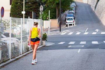 End of a run in Nice. A female runner with a water bottle on her belt on the street of the French city after a workout.